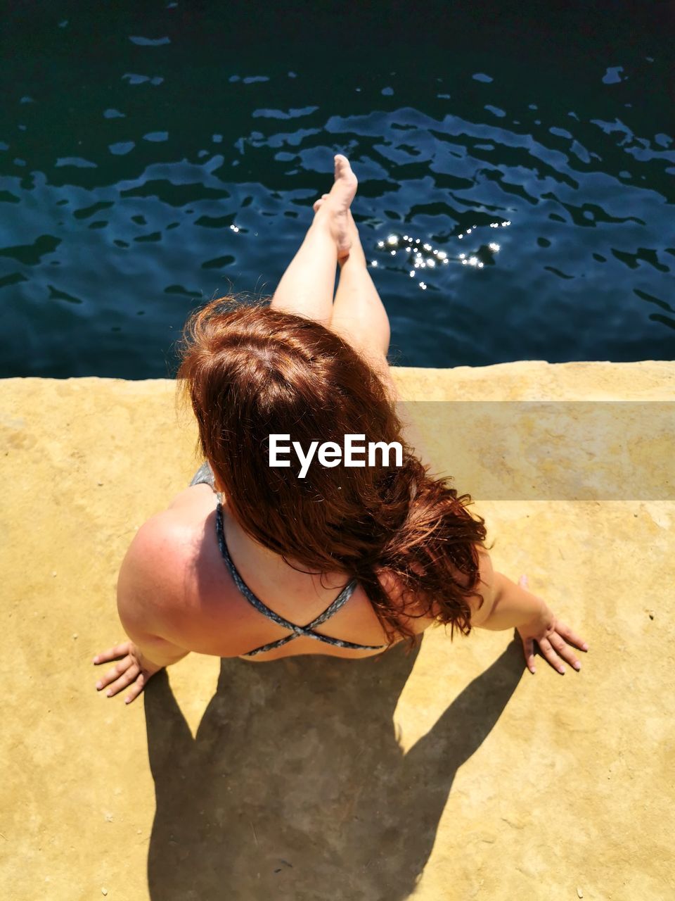 High angle view of woman sitting by sea