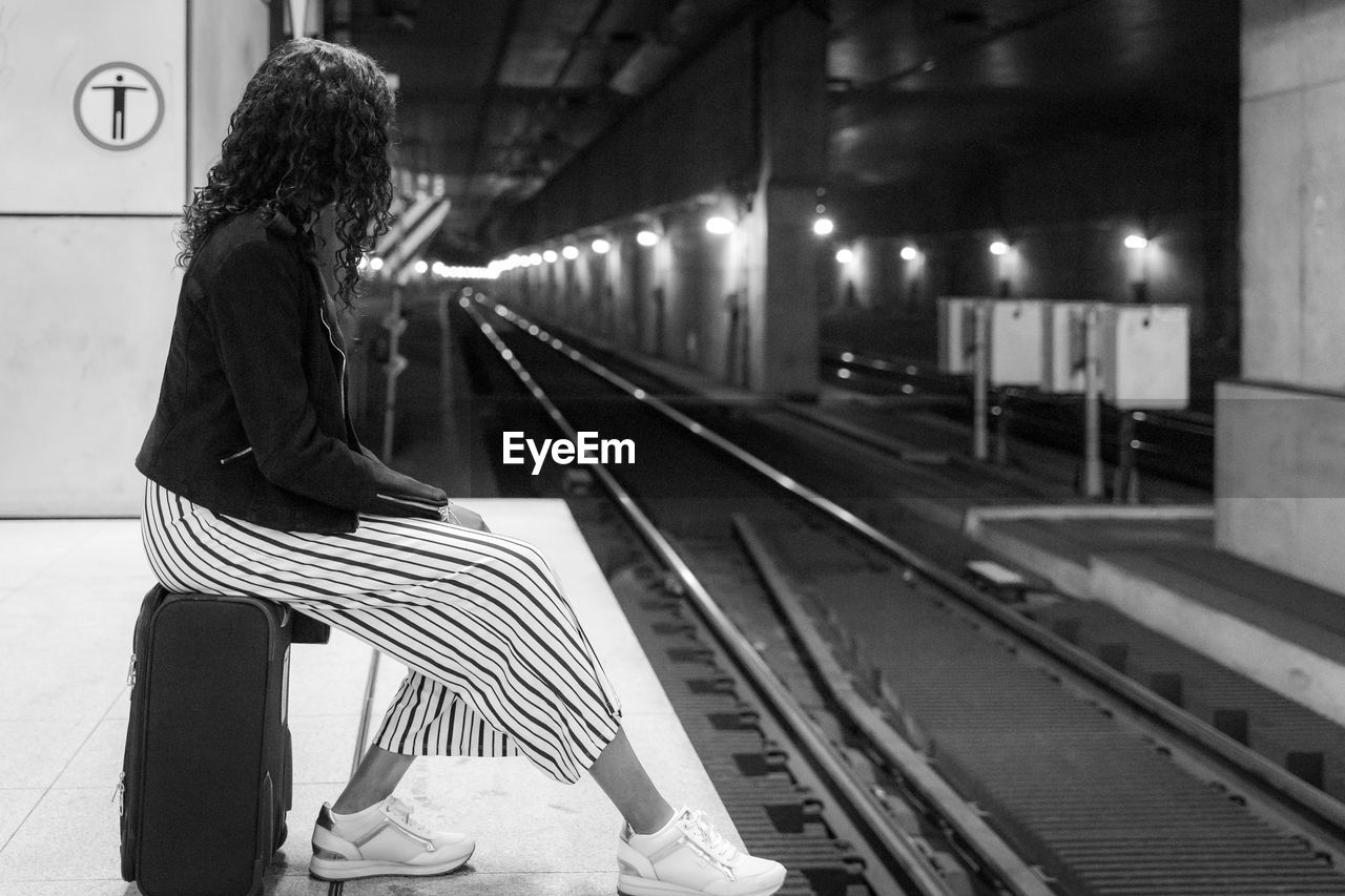 Woman looking away while sitting at railroad station platform