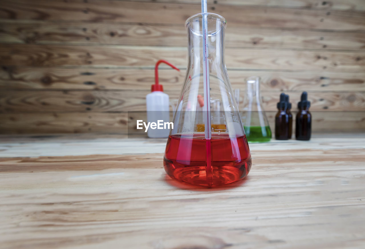 red, indoors, wood, research, container, science, no people, table, scientific experiment, healthcare and medicine, glass, bottle, education, laboratory, still life, laboratory glassware, chemistry, close-up