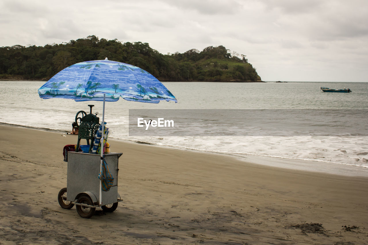 MOTORCYCLE ON BEACH AGAINST SKY