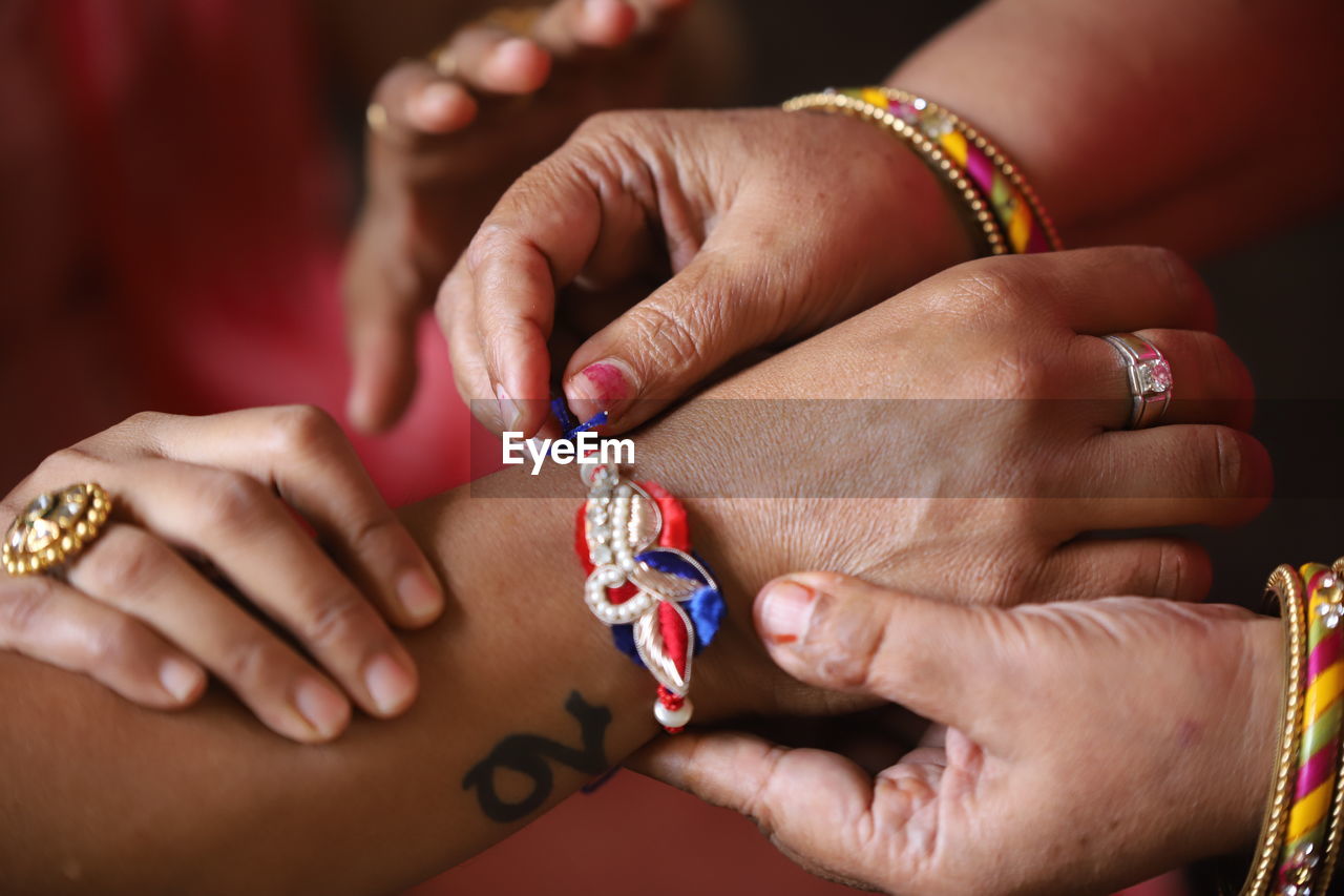 Cropped hands of sister tying rakhi of hand of brother