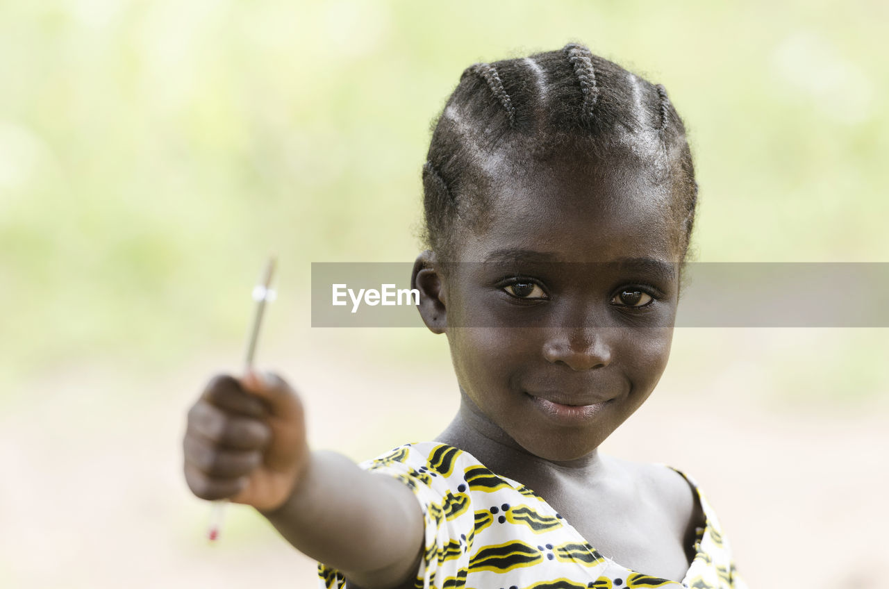 Portrait of girl holding pen outdoors