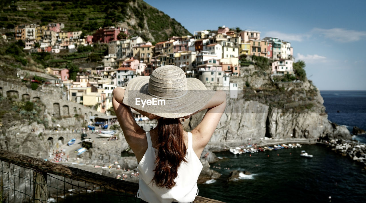 Rear view of woman standing against buildings at vernazza