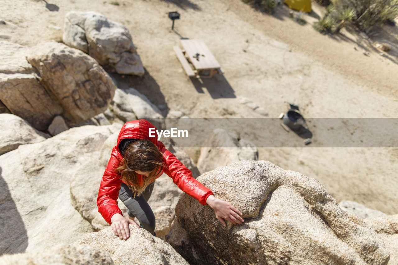 High angle view of hiker climbing rocks at joshua tree national park during sunny day