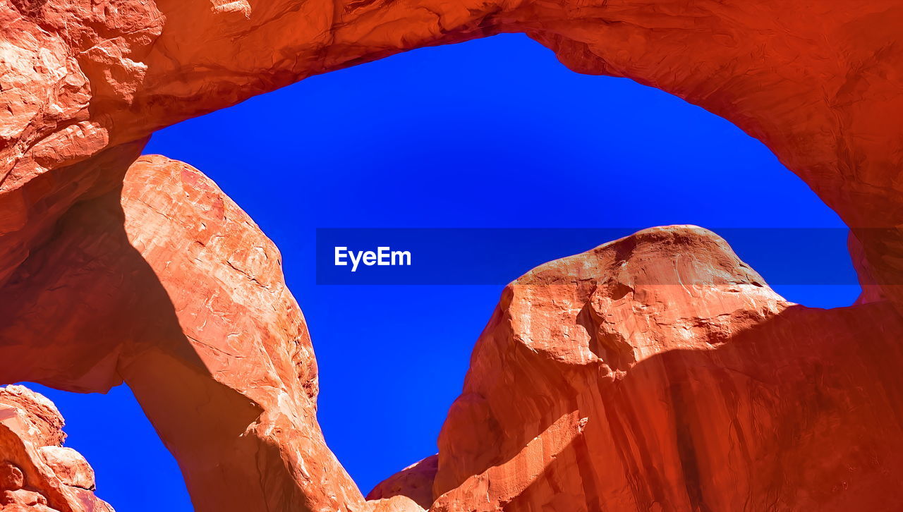 Low angle view of rock formation against clear blue sky stone around