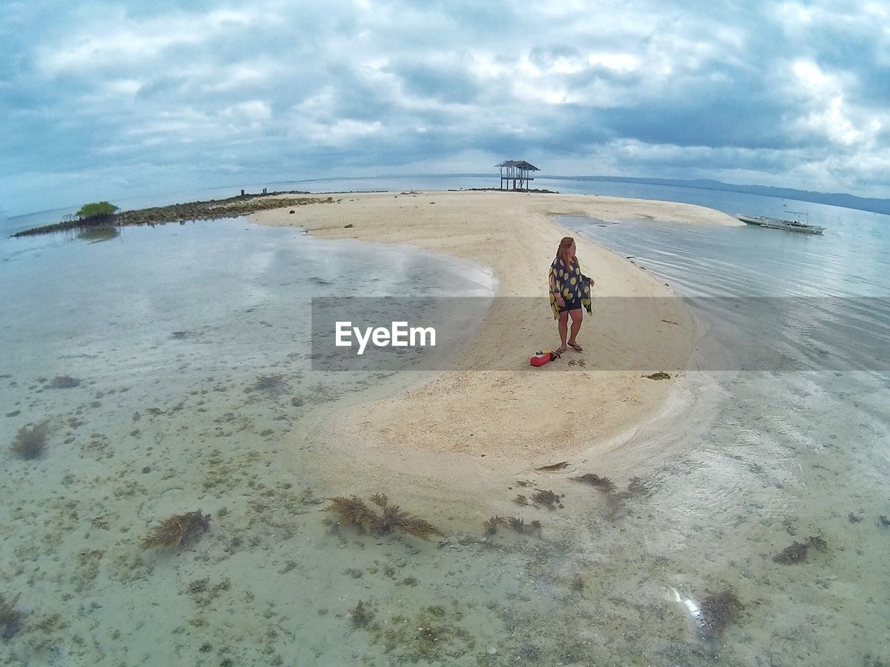 Scenic view of woman standing on beach against sky