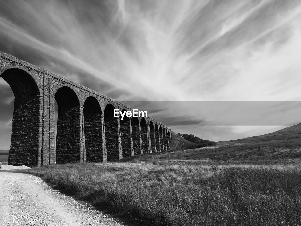 Arch bridge on field against sky