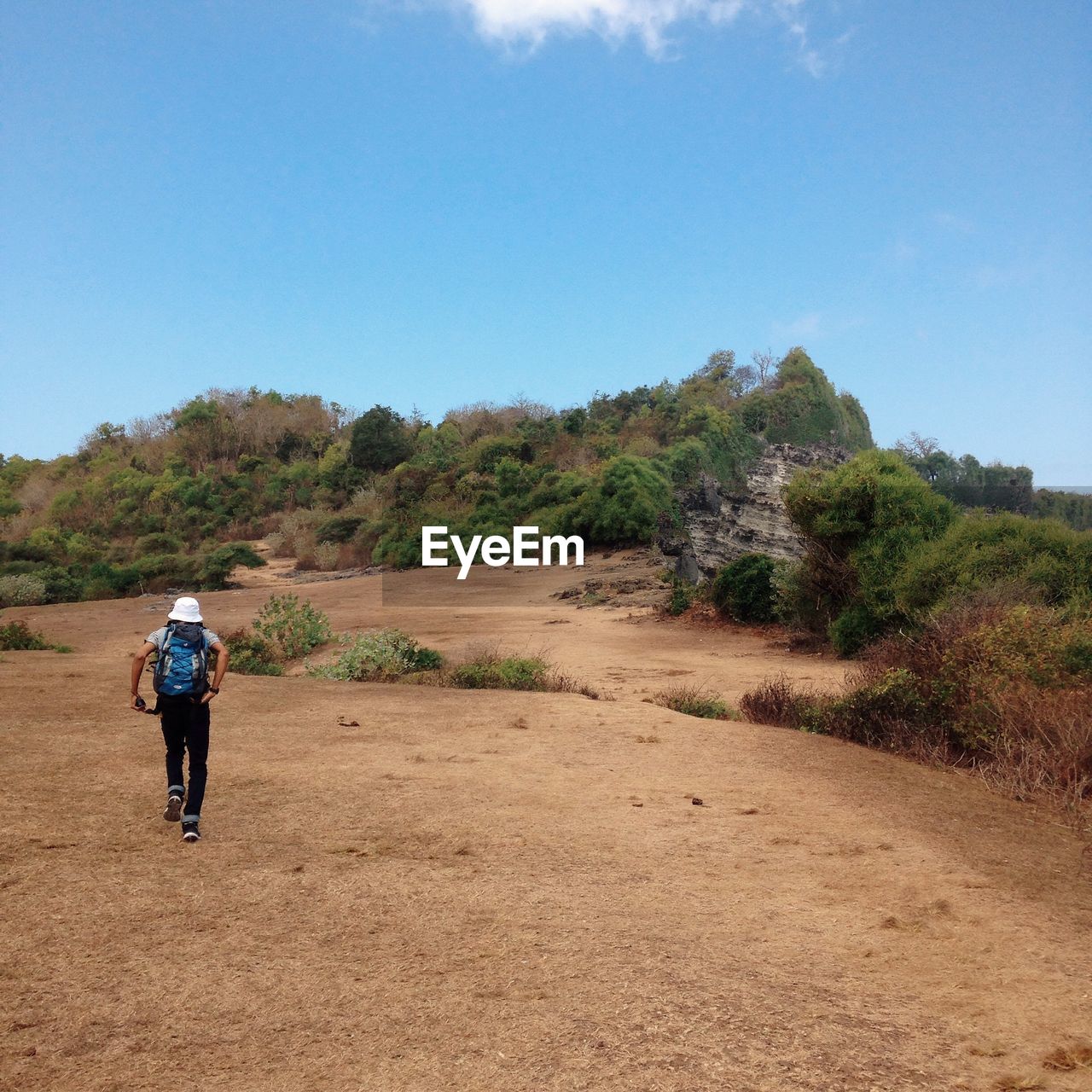 Rear view of hiker walking on field