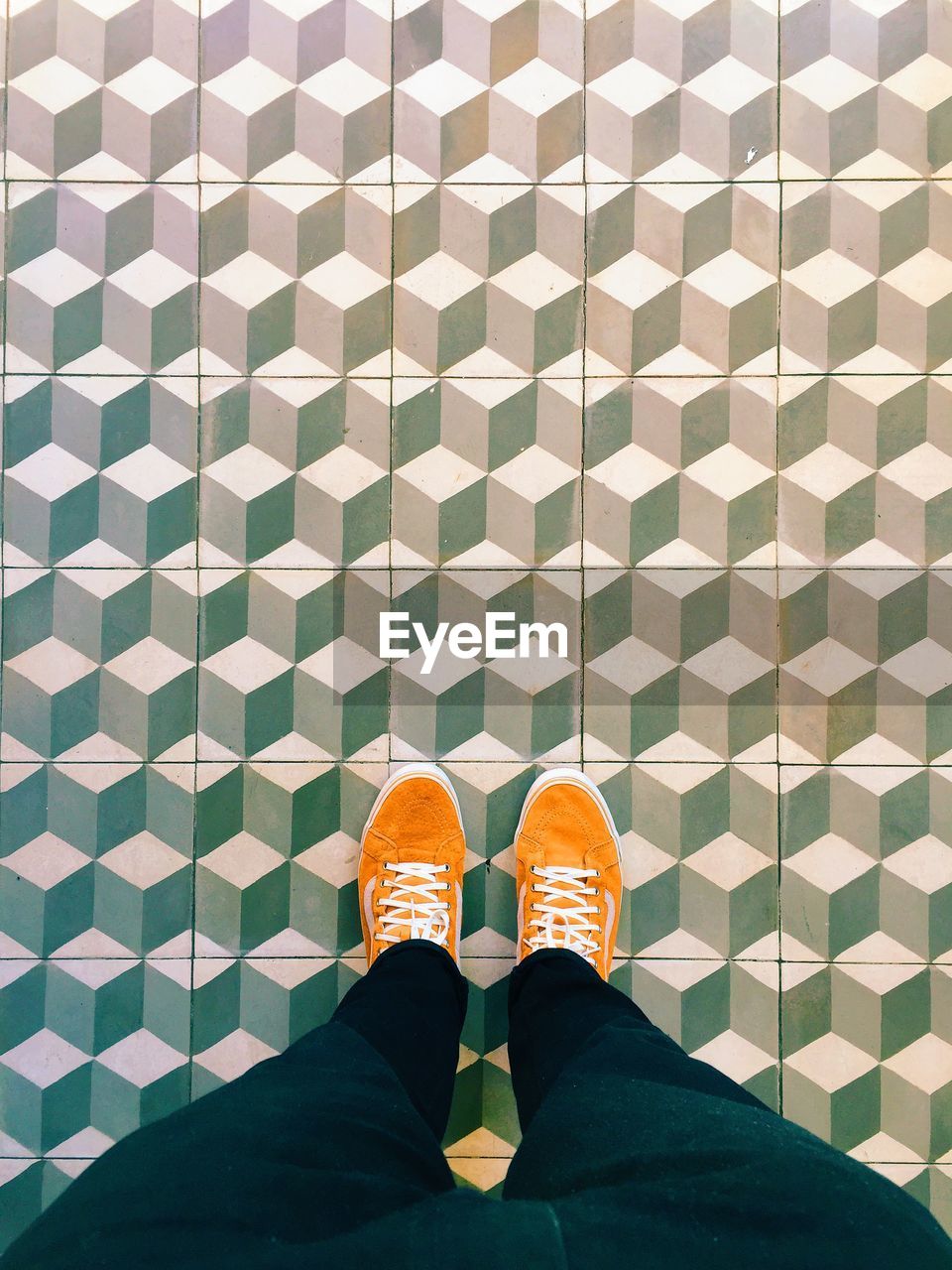 Woman in orange shoes standing on tiled floor 