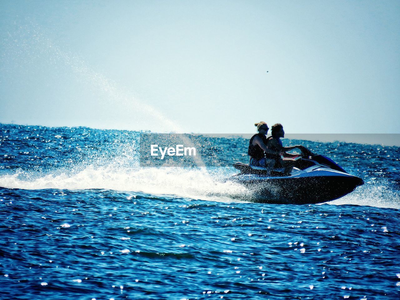 PEOPLE RIDING ON SEA AGAINST CLEAR SKY