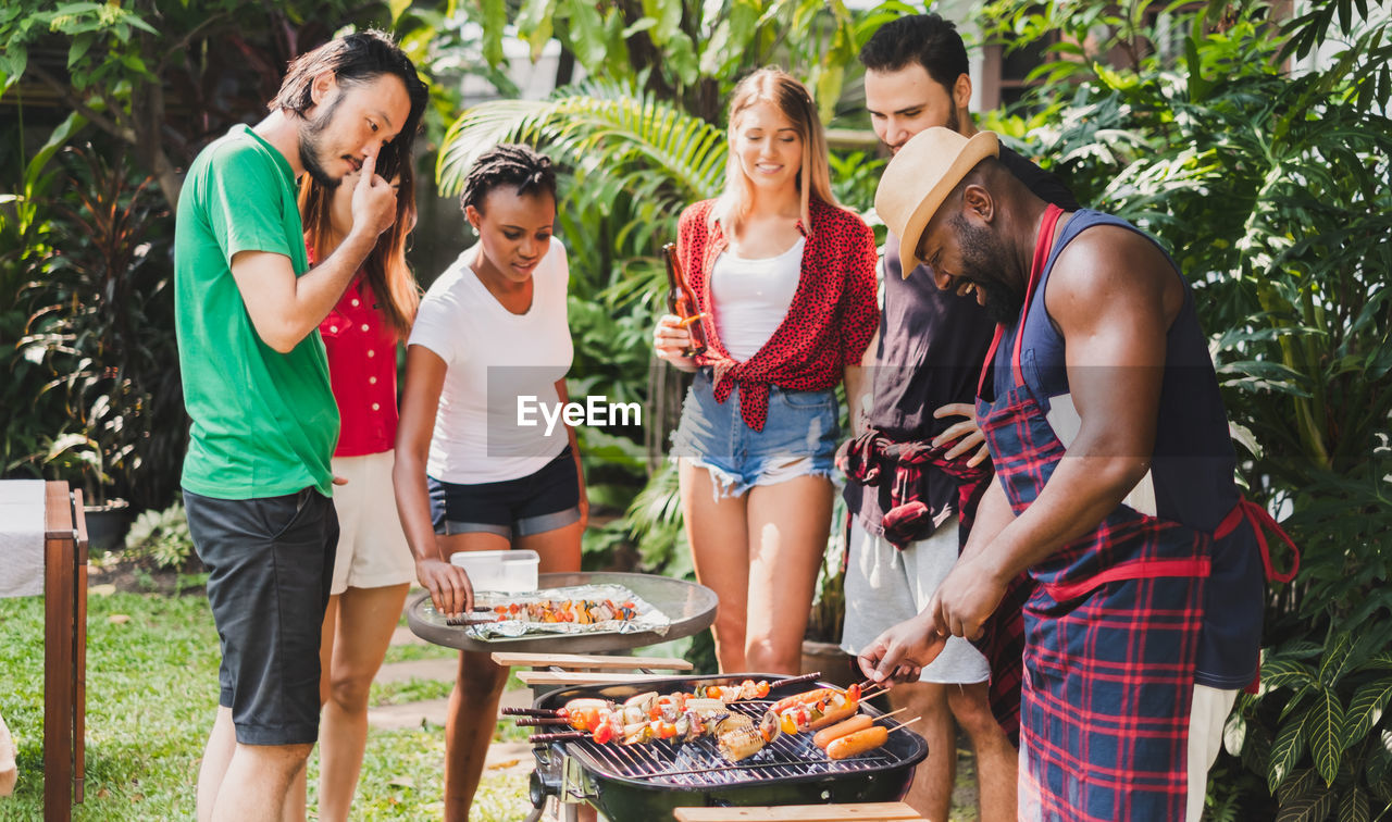 Friends enjoying barbecue while standing outdoors