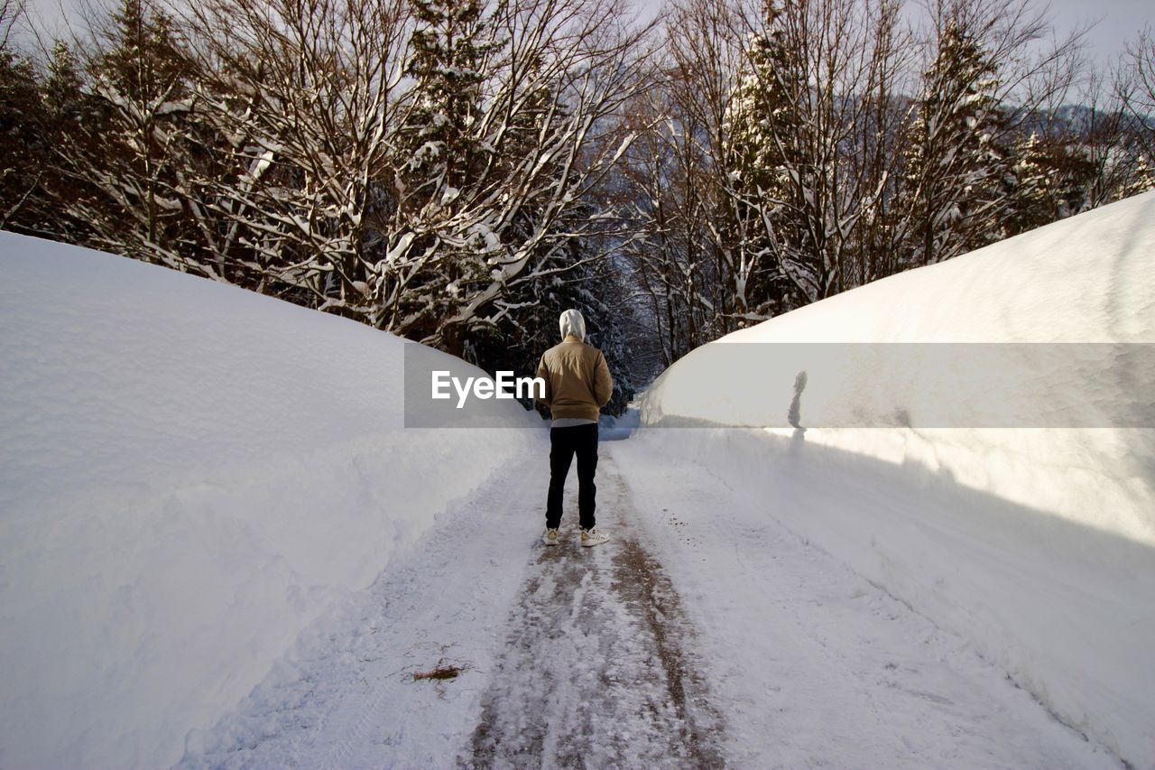Rear view of man standing on snow covered road