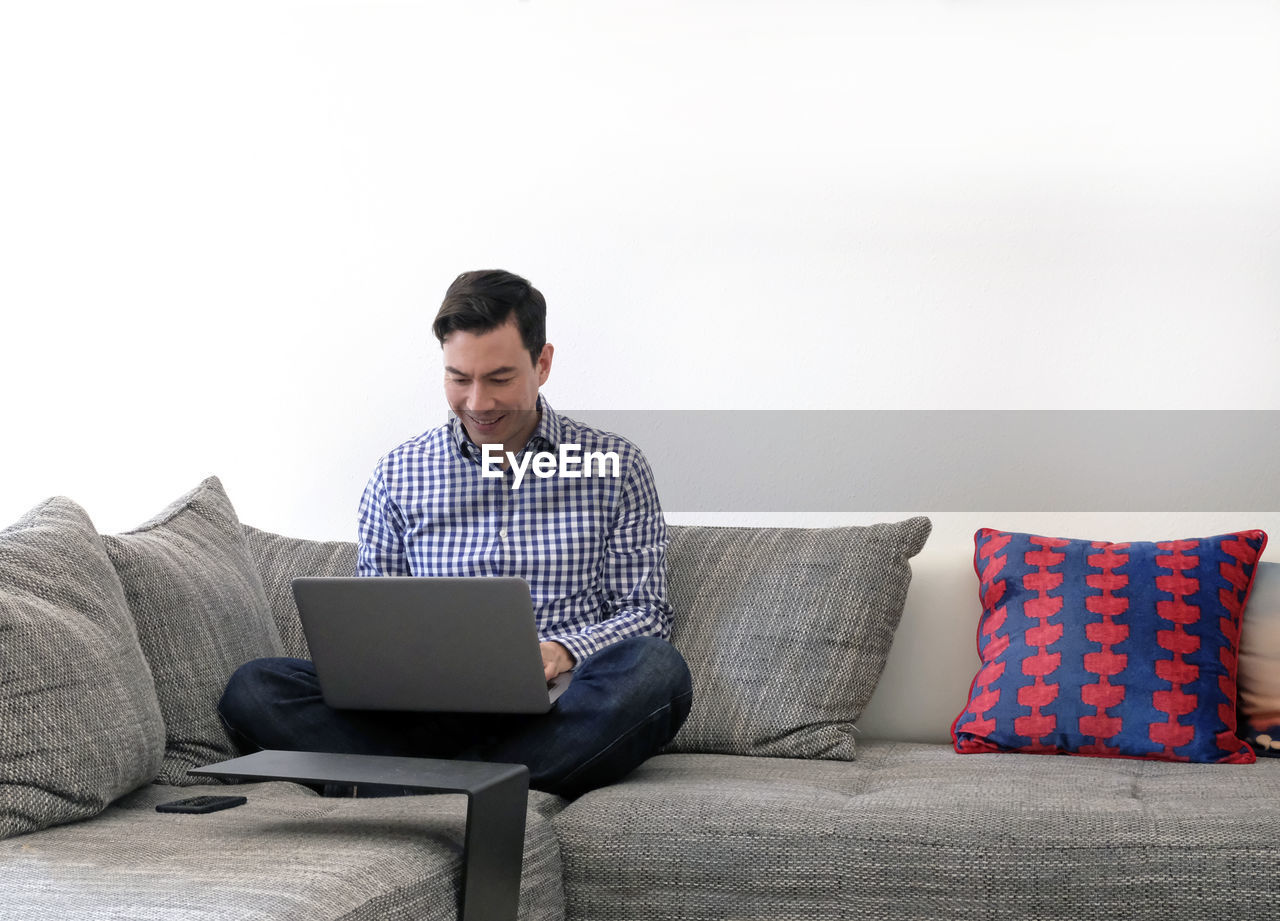 Man using laptop while sitting on sofa at home