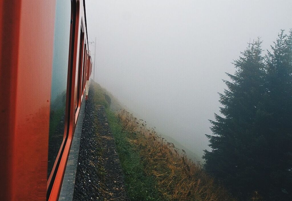 Railroad car on mountain in foggy weather against clear sky