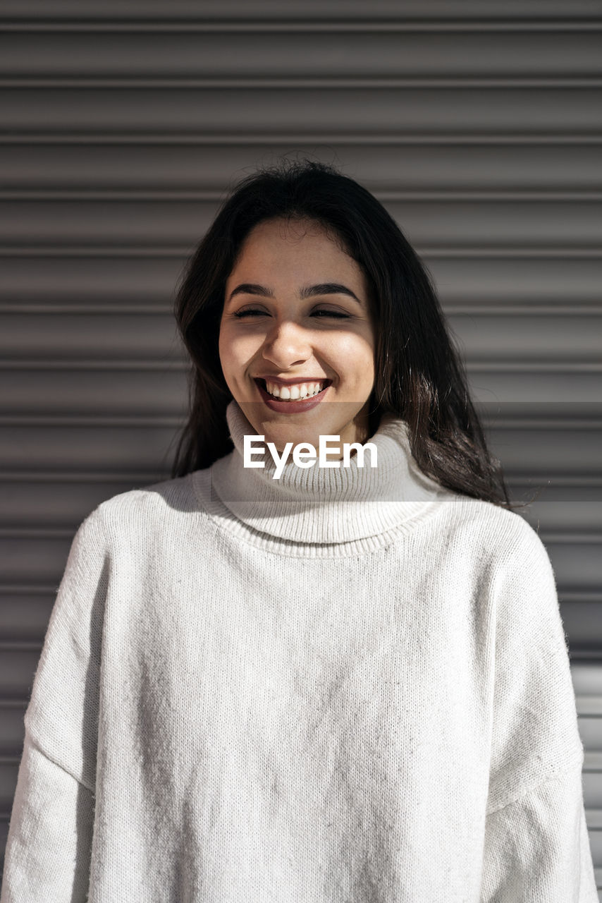 Young smiling woman standing against shutter