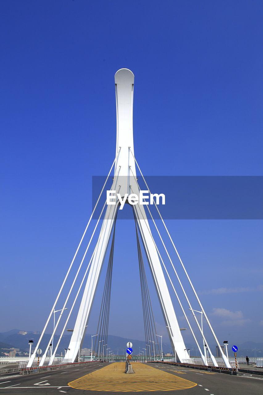 LOW ANGLE VIEW OF SUSPENSION BRIDGE AGAINST BLUE SKY