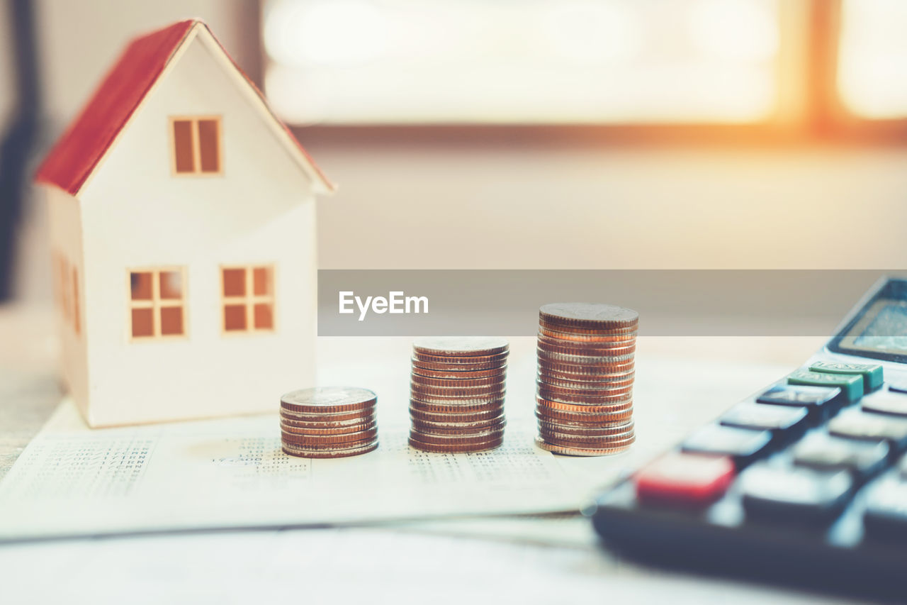 Stack of coins with model house on table