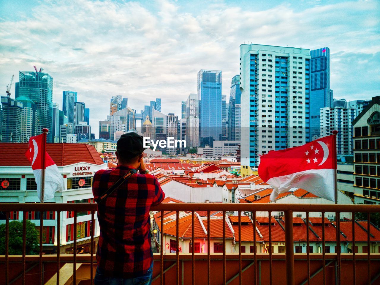 REAR VIEW OF MAN STANDING AGAINST MODERN BUILDINGS IN CITY