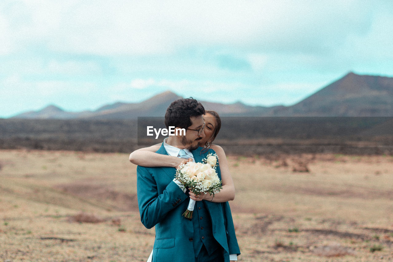 Side view of young man and woman standing on volcanic landscape 