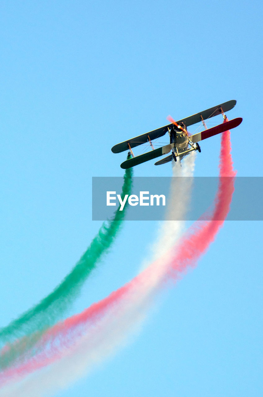 Low angle view of airplane flying against clear blue sky