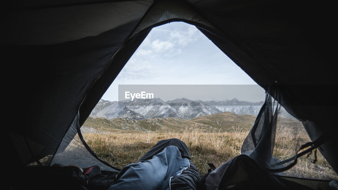 Low section of person in tent against mountains