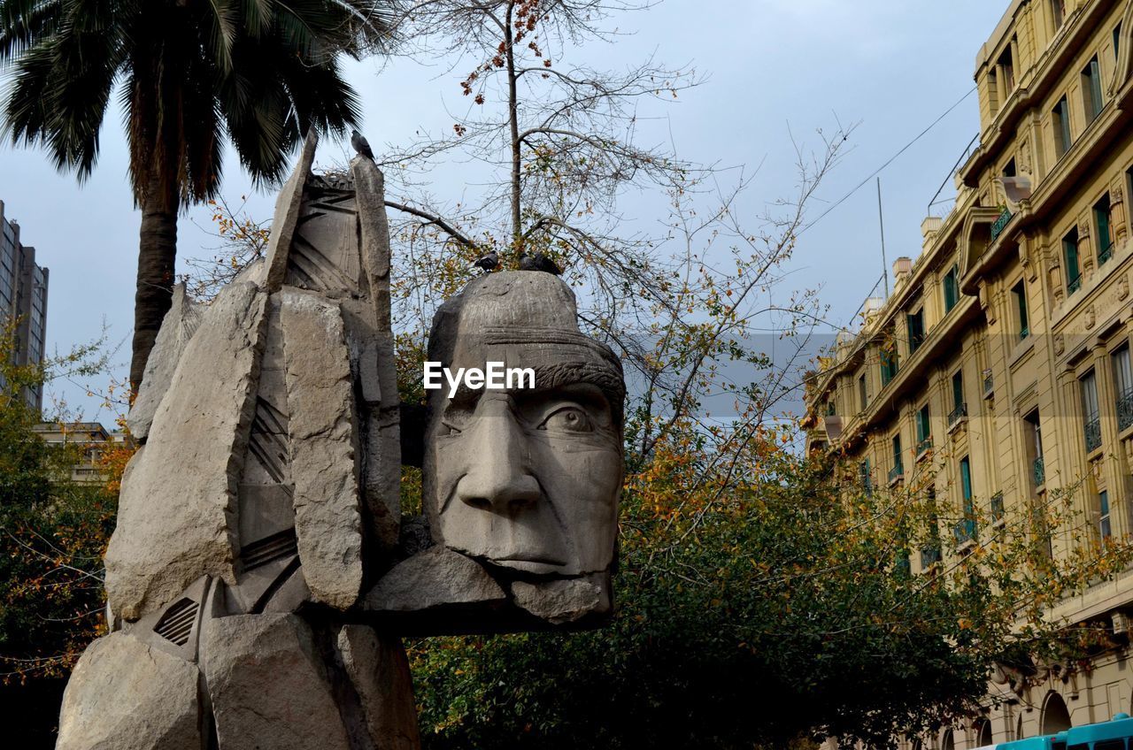 LOW ANGLE VIEW OF STATUE AGAINST TREES AND BUILDING