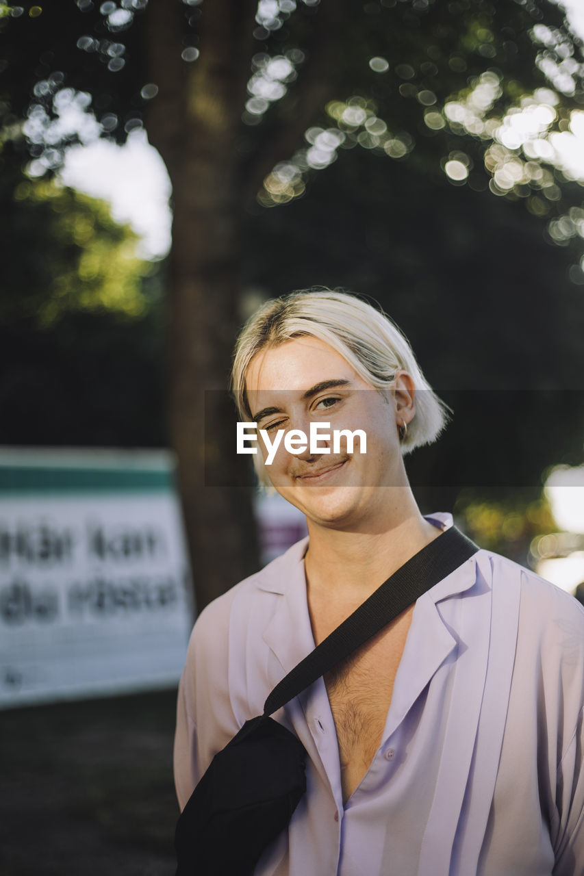 Portrait of smiling non-binary person with medium-length hair winking eye