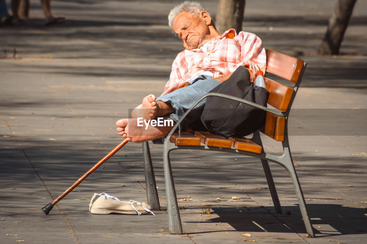 Senior man sleeping on bench at park