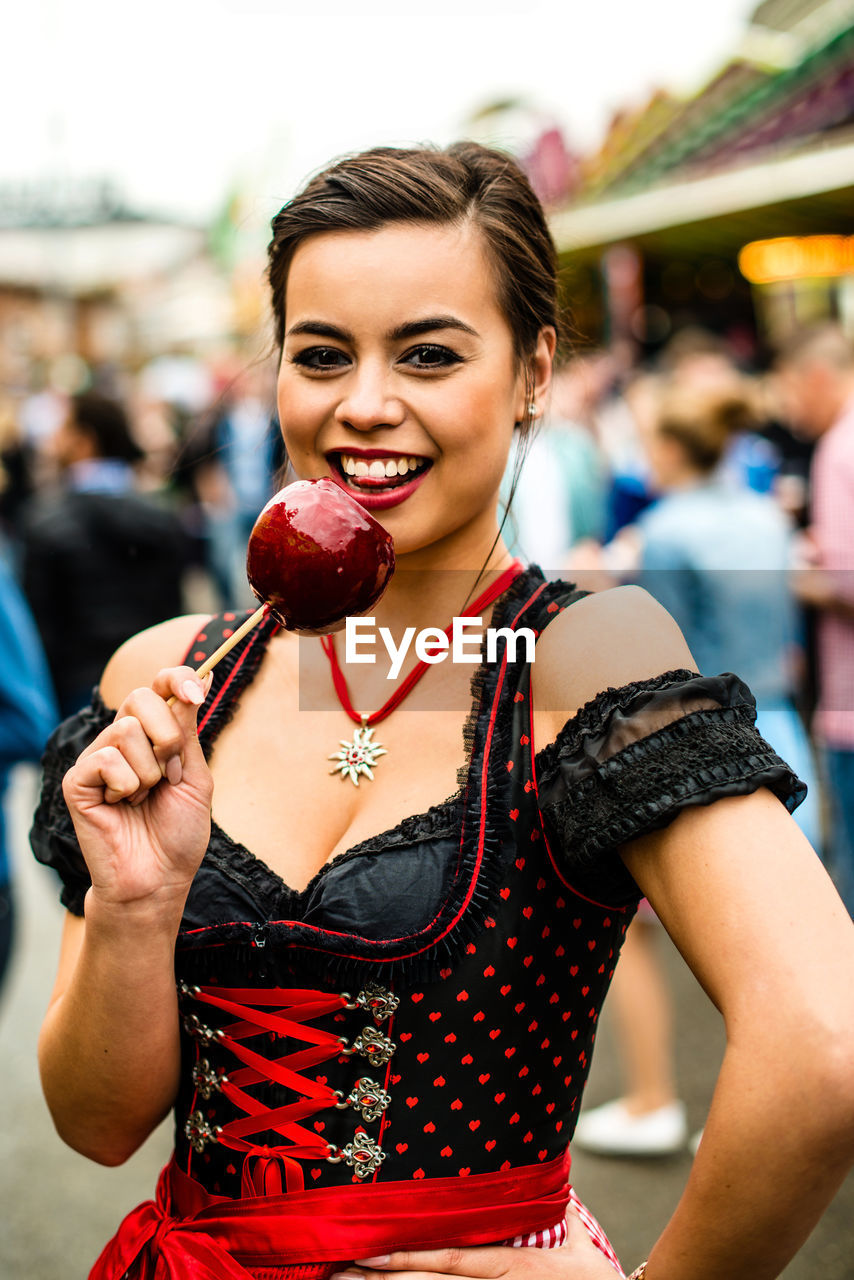 Portrait of beautiful happy woman holding candy at oktoberfest