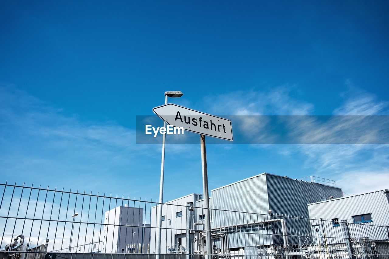 Low angle view of road sign against blue sky