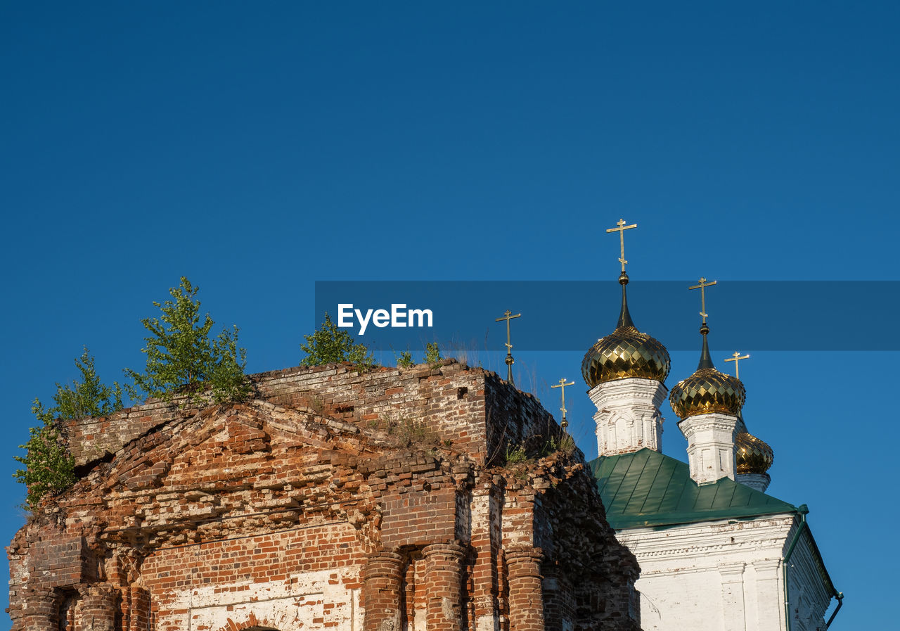 Golden domes and green trees over an ancient temple in the village of stromikhino, ivanovo region.