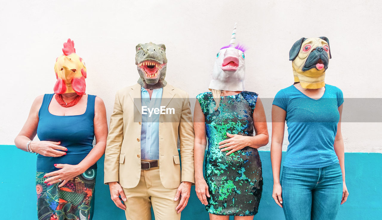 Full length of people wearing mask while standing against wall