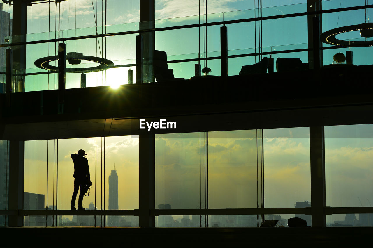 Silhouette man standing in modern building during sunset