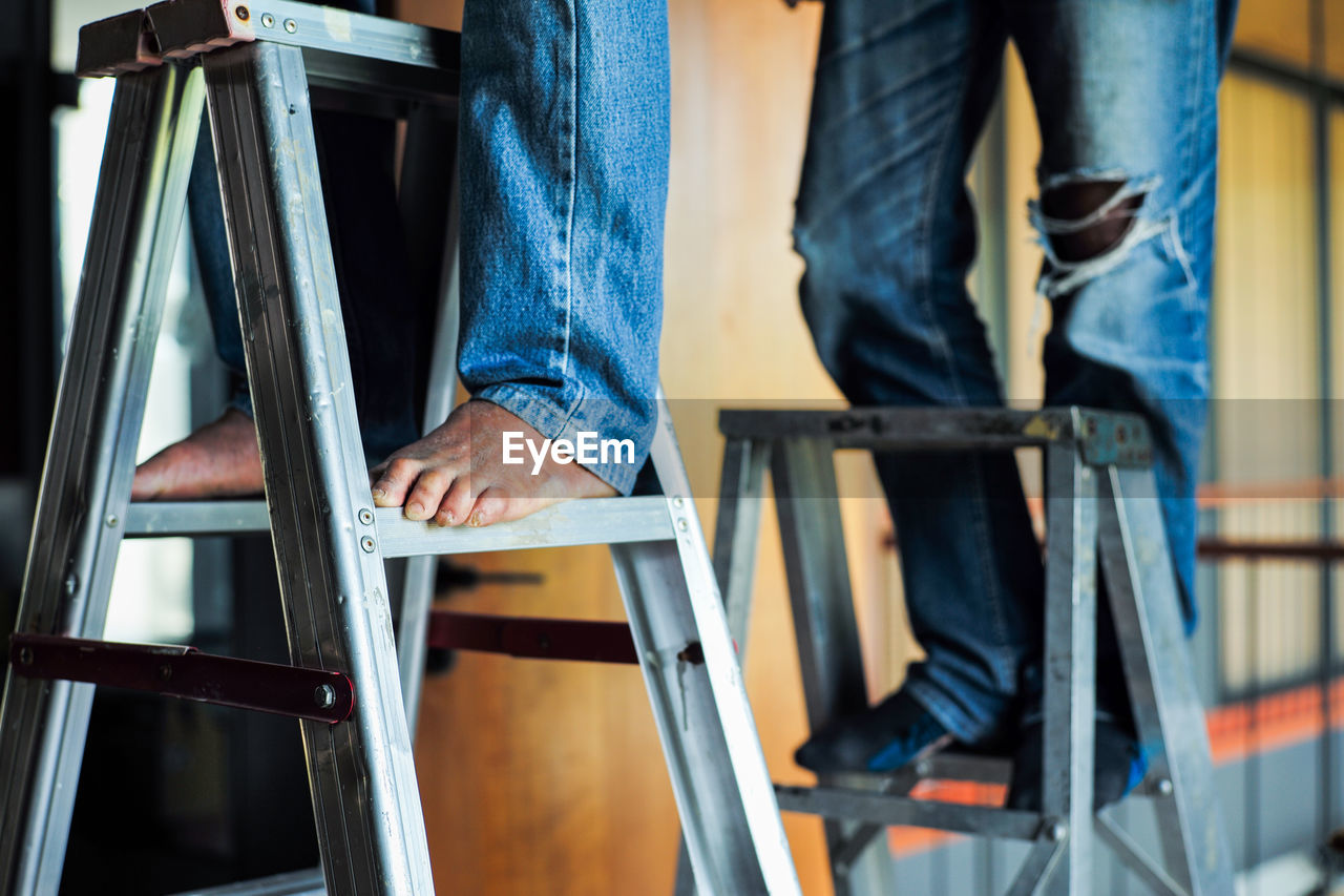 Selective focus on the aluminum ladder with defocused feet of workers working on it