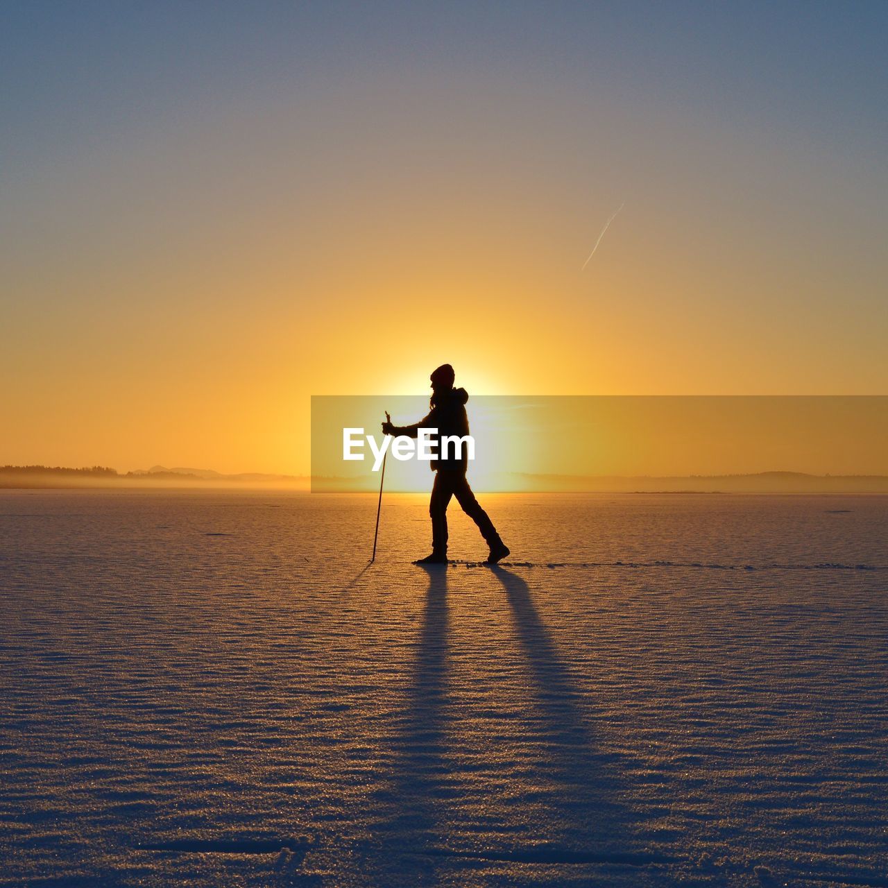 Silhouette man on snow against sky during sunset