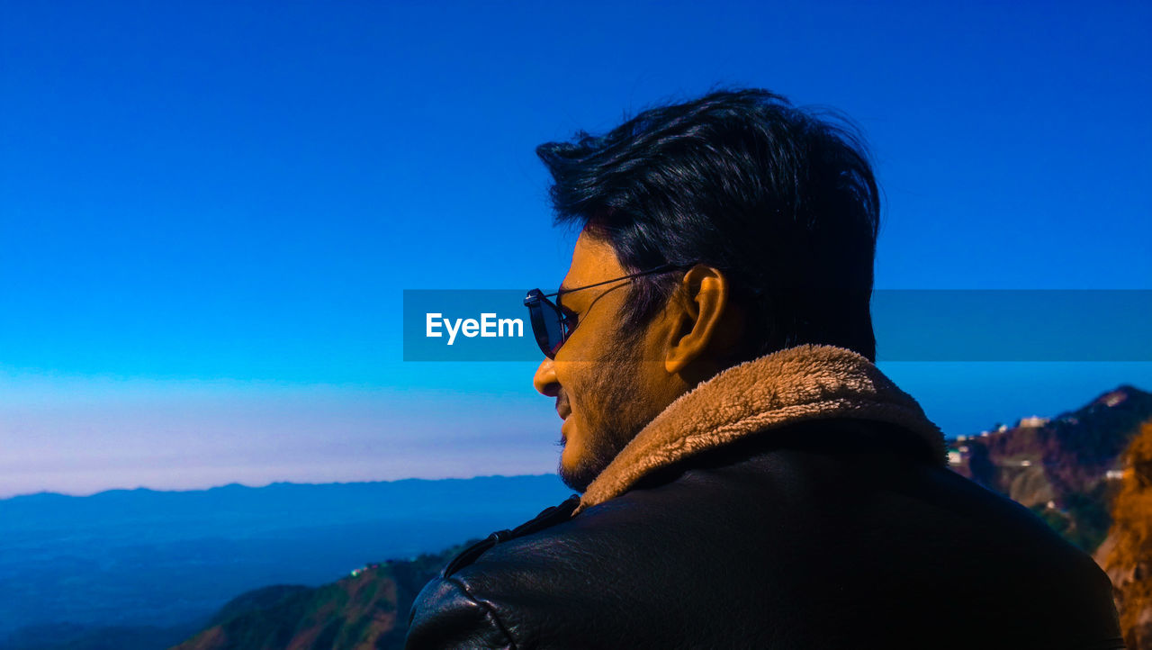 Close-up of man looking away against clear sky