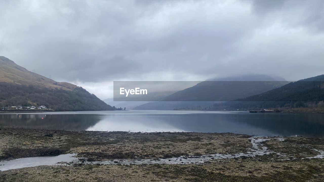 water, mountain, lake, cloud, environment, scenics - nature, sky, highland, beauty in nature, landscape, reservoir, body of water, nature, land, mountain range, beach, travel destinations, fog, overcast, tranquility, no people, travel, tranquil scene, dramatic sky, coast, reflection, tourism, glacial landform, bay, non-urban scene, outdoors, storm cloud, cold temperature, dramatic landscape, water's edge, day, lakeshore, storm, cloudscape, shore