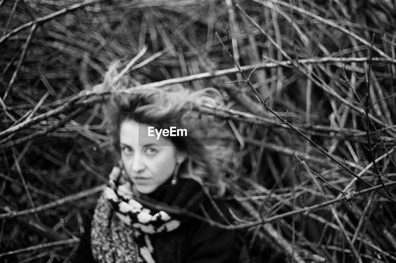 black and white, portrait, one person, plant, land, monochrome photography, young adult, tree, forest, monochrome, women, looking at camera, nature, adult, headshot, outdoors, day, black, clothing, hairstyle, focus on foreground, portrait photography, looking, front view, human face, female, winter, emotion, branch, leisure activity