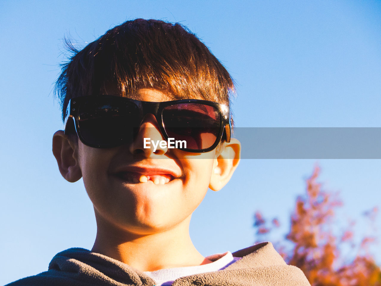 Portrait of boy wearing sunglasses against clear blue sky
