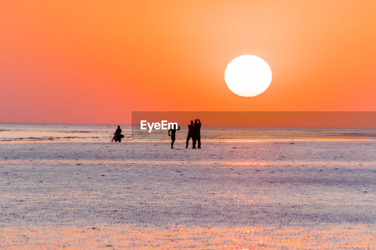 SILHOUETTE PEOPLE ON BEACH AT SUNSET