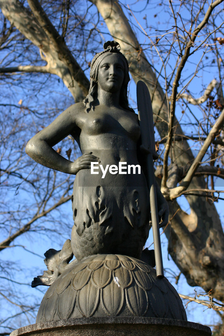 LOW ANGLE VIEW OF STATUES AGAINST BARE TREES