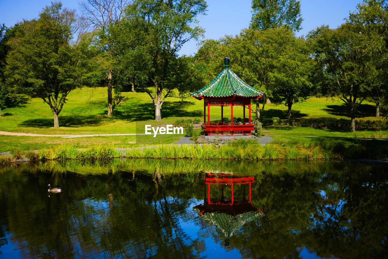 Scenic view of gazebo in the park with reflection on the lake against trees