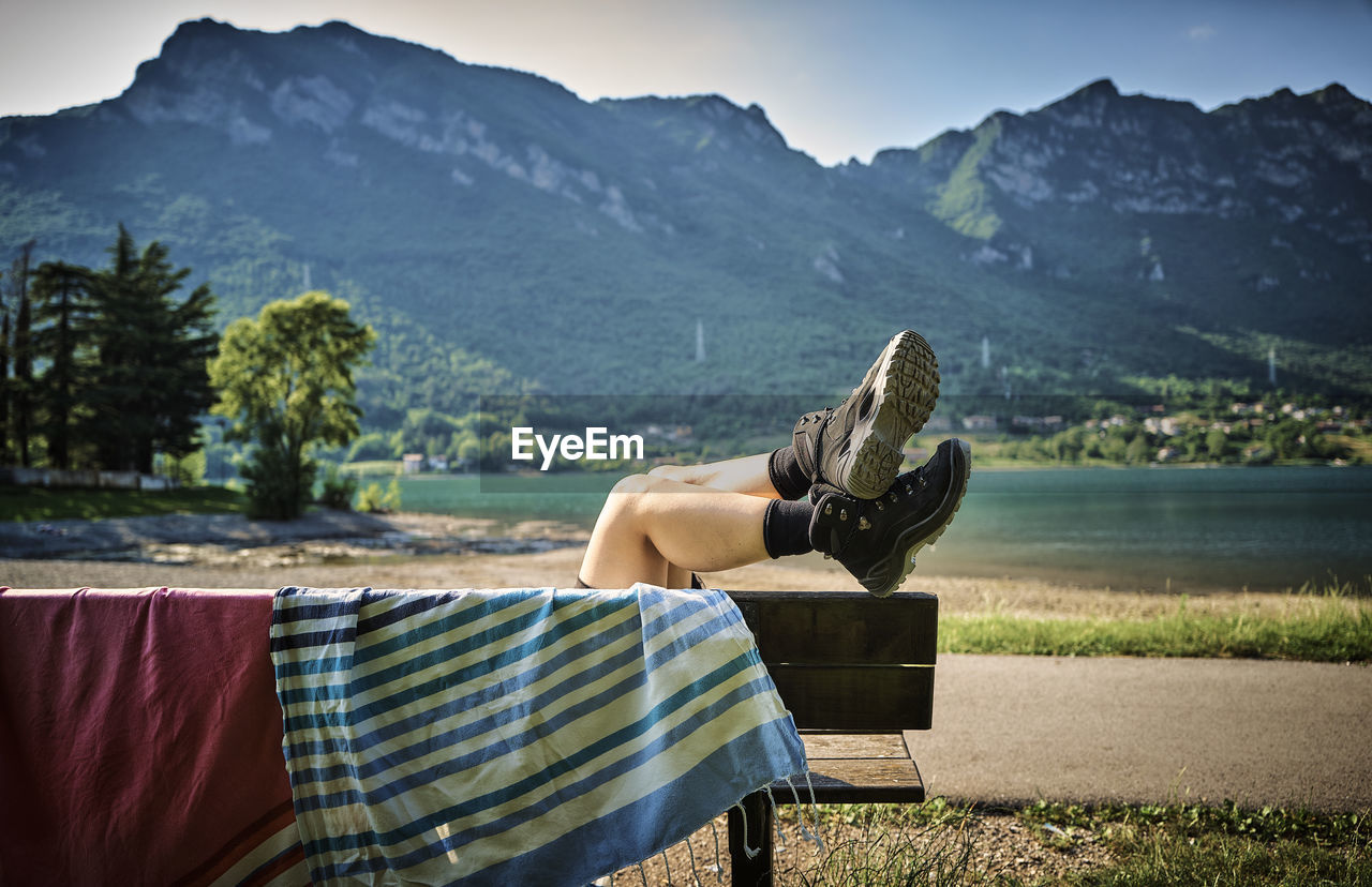 Legs of woman wearing hiking boots relaxing on bench with towel