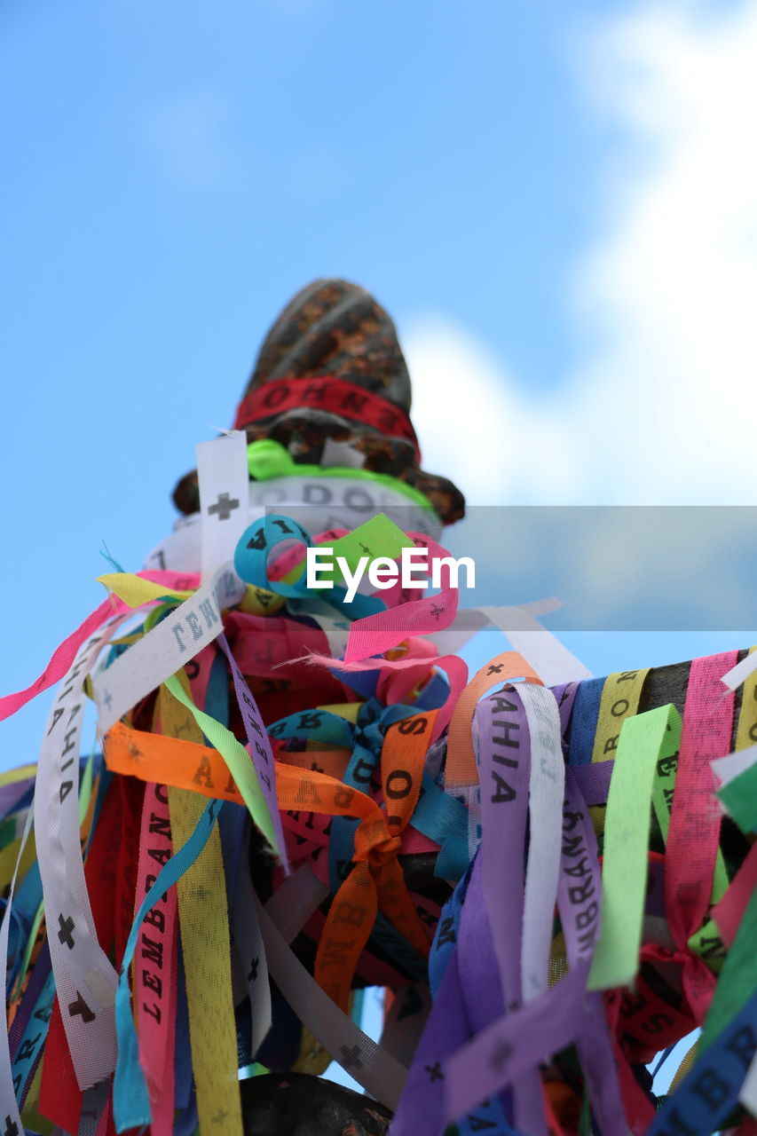 LOW ANGLE VIEW OF MULTI COLORED HANGING ON STACK AGAINST SKY