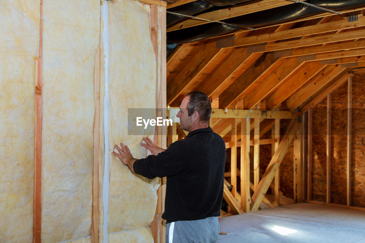 Side view of man examining work in incomplete home