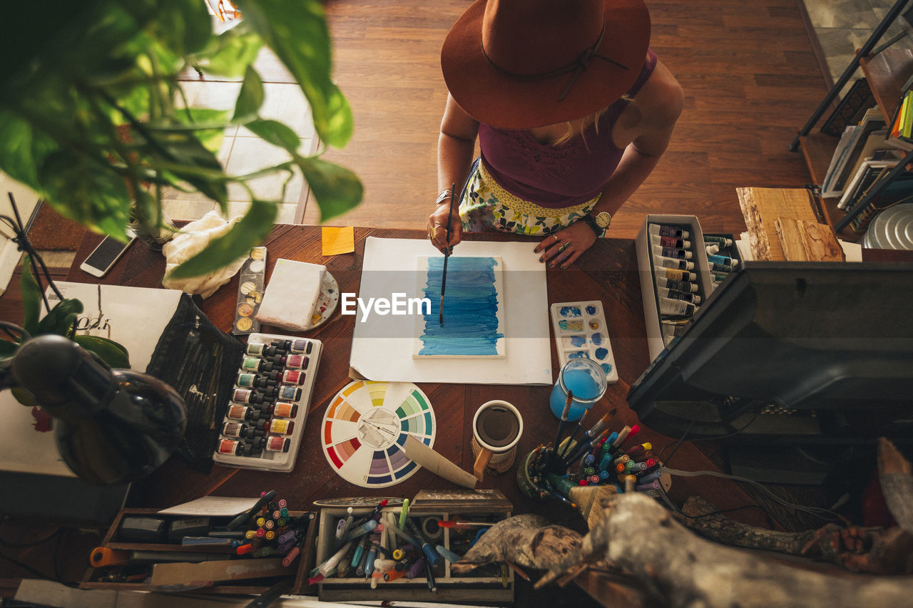 High angle view of artist painting on table while standing at home