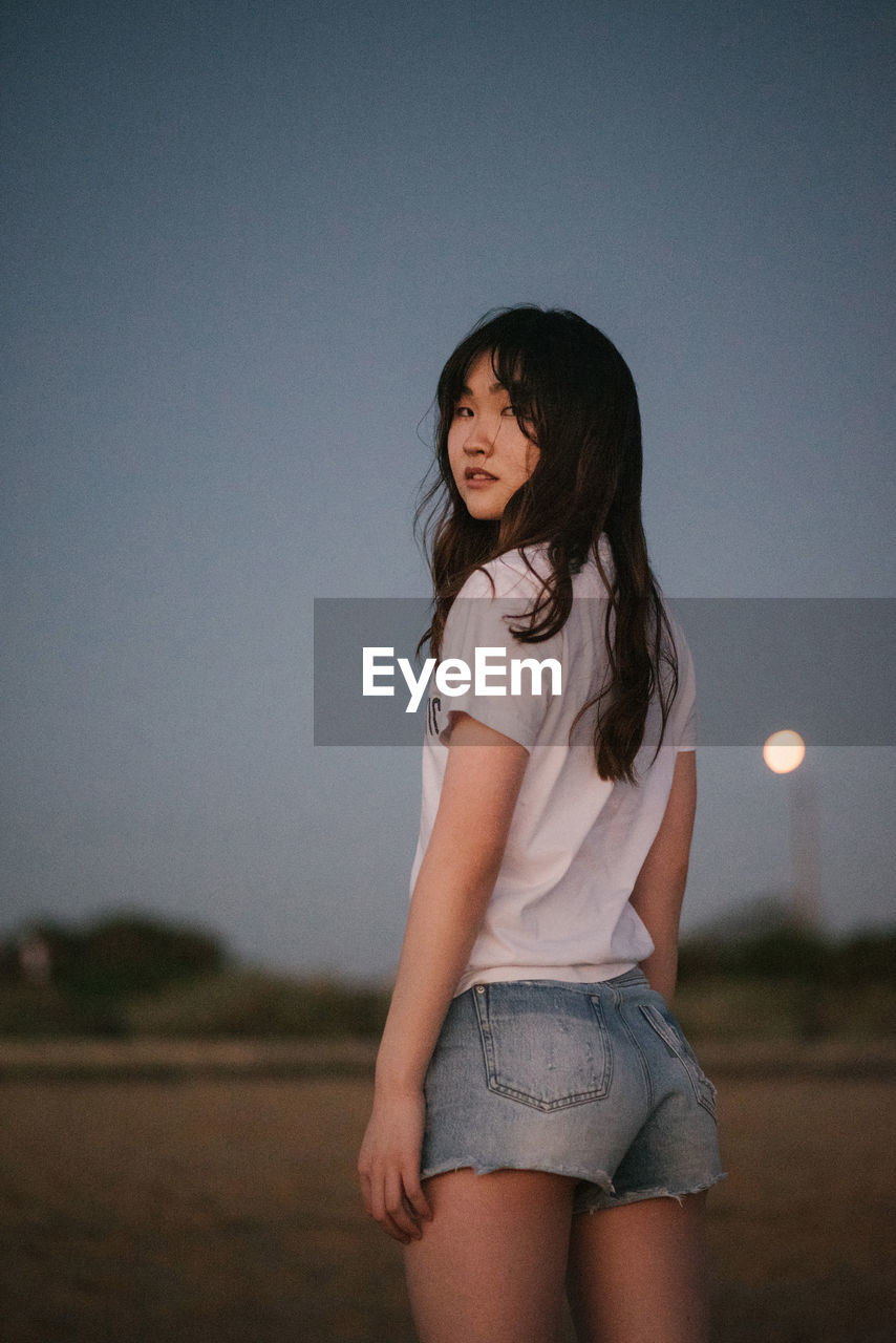 An asian girl on a beach. hair, jeans, sunset