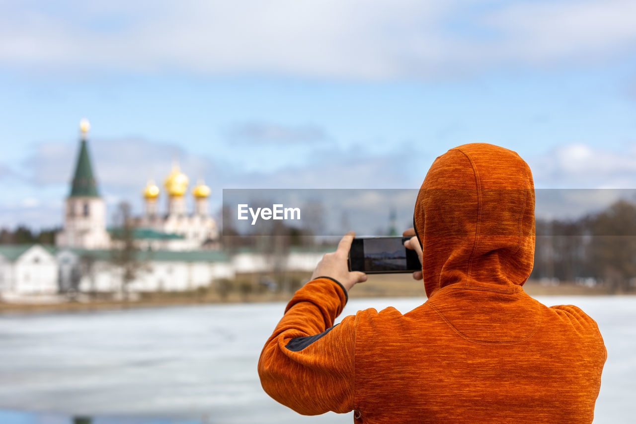 Rear view of man photographing against sky