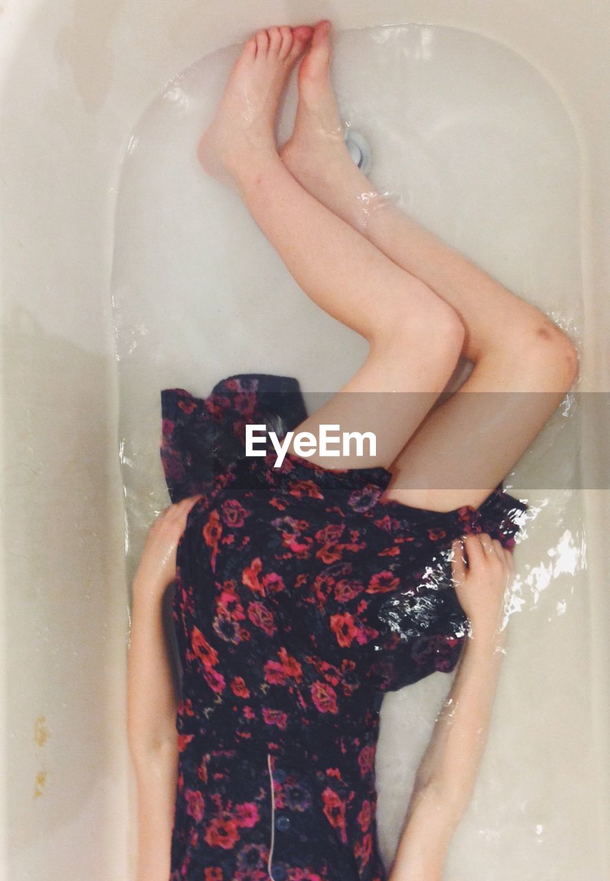 Low section of woman lying in bathtub