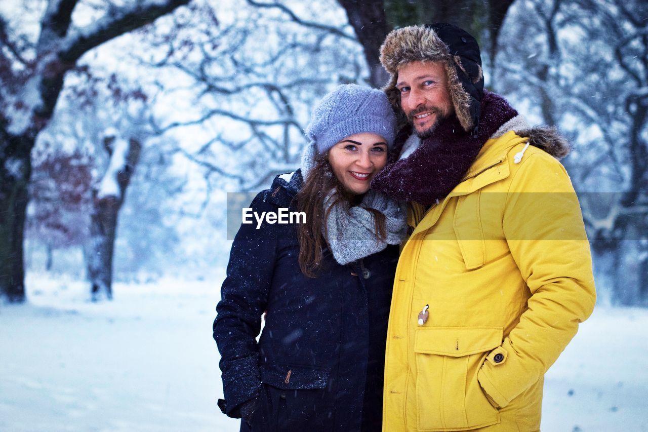 Portrait of smiling people standing on snowy field